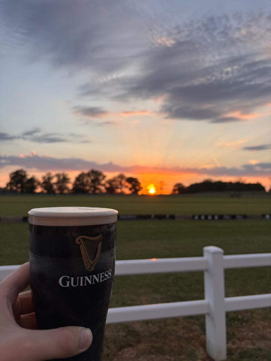 A pint of Guinness against the polo field at sunset