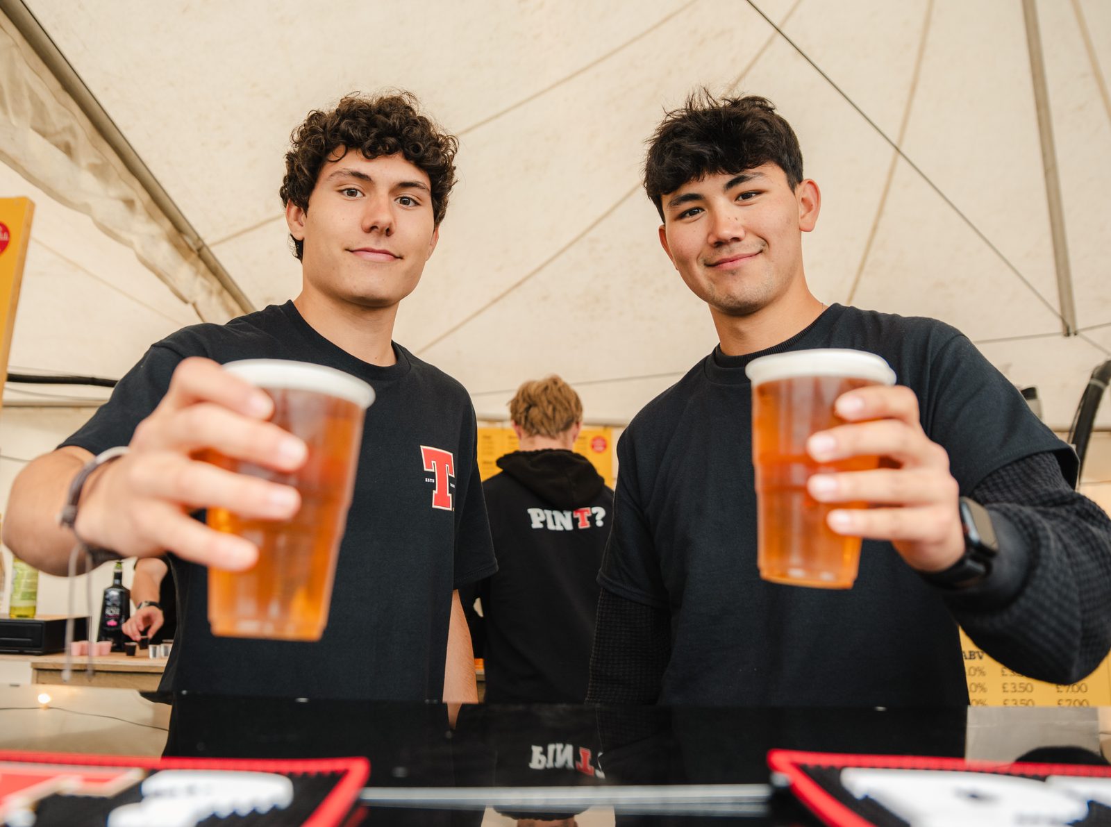Two Apex bar team members holding up pints